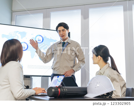 大画面モニターの前でミーティングする作業員のグループ 123302905