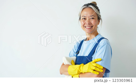 Portrait adult Asian Woman in blue apron and yellow rubber gloves with rag in his hand near white wall with free place for text, window cleaning service, house cleaning, maid. AI generated 123303961
