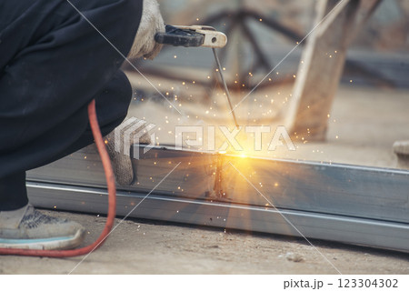 Construction Worker hands using Welding machinery iron metal sparking. Men hands wear protective glove Hot flame metal work cutting fire iron workshop. Locksmith use Welding machine cut metal process 123304302