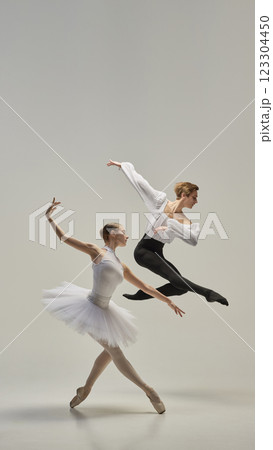 Ballet dancers performing synchronized leap, arms and legs fully extended in fluid, weightless motion against white studio background. Ballet dancers performing synchronized leap, arms and legs fully extended in fluid, weightless motion against white studio background. 123304450