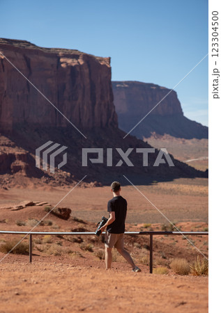 Photographer exploring the vast landscape of Monument Valley. Young man with camera walking in Monument Valley area. Concept of adventure, travel, creativity, and solitude in nature. 123304500