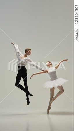 Two ballet dancers, man and woman, dancing classic ballet moves, leaping in motion, elegantly raising hands against white studio background. 123304507