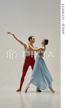 Ballet partners moving in perfect unison, gazes locked, hands delicately connected, elegance captured in fluid pose against white studio background. Ballet partners moving in perfect unison, gazes locked, hands delicately connected, elegance captured in fluid pose against white studio background. 123304551
