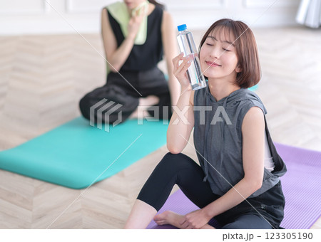 ヨガマットに座ってペットボトルを持つ若い女性 ヨガマットに座ってペットボトルを持つ若い女性 123305190