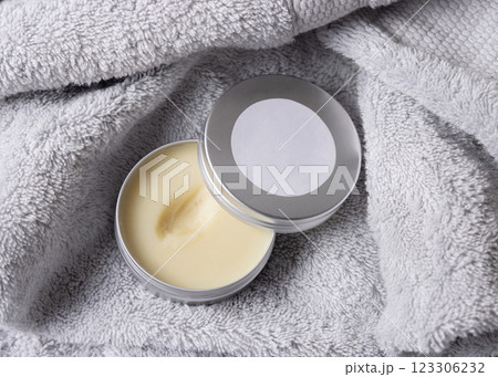 Opened body butter jar with blank label on light grey bath towel close up, cosmetic mockup 123306232