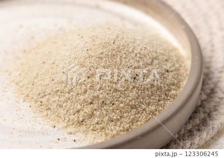 Raw uncooked fonio seeds on a plate on white table, top view. African ancient pseudocereal 123306245