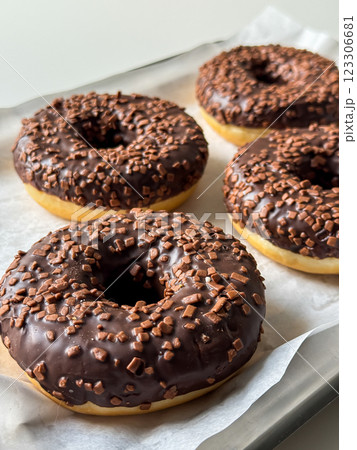 Brown chocolate donuts on metal tray and white table close up Brown chocolate donuts on metal tray and white table close up 123306681