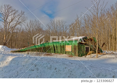 Old green barn collapses due to age and heavy snow load in winter 123306827