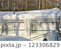 Large icicles and ice dams form at the edge of the snow-covered roof above frozen eavestrough gutter 123306829