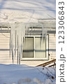 Large icicles and ice dams form at the edge of the snow-covered roof above frozen eavestrough gutter 123306843
