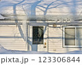 Large icicles and ice dams form at the edge of the snow-covered roof above frozen eavestrough gutter 123306844