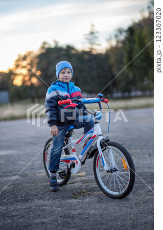 Young boy rides a bicycle during sunset in a rural setting 123307020
