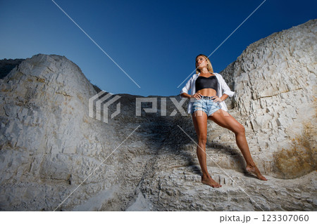 Young woman in shirt and shorts posing in a rugged outdoor landscape at dusk Young woman in shirt and shorts posing in a rugged outdoor landscape at dusk 123307060