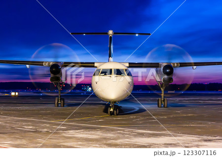 Front view of a white passenger turboprop airplane taxis through an airport at dawn 123307116