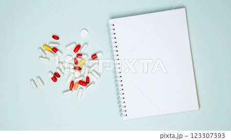 Concept of medicine, healthcare, pharmaceutical industry. Blister of tablets with pills and blank notebook Concept of medicine, healthcare, pharmaceutical industry. Blister of tablets with pills and blank notebook 123307393