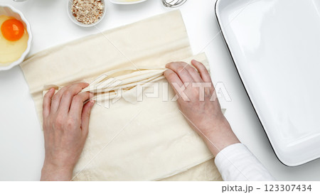Baking Crinkle Cake., hands folding phyllo dough with egg, butter, nuts, milk 123307434