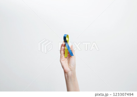 A person holds a yellow and blue awareness ribbon, symbolizing World Down Syndrome Day A person holds a yellow and blue awareness ribbon, symbolizing World Down Syndrome Day 123307494