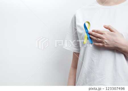 A person wearing a white t-shirt with a yellow and blue awareness ribbon, symbolizing World Down Syndrome Day 123307496