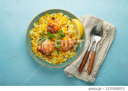 Traditional Indian dish chicken biryani with cilantro and lemon in a bowl top view on blue background Traditional Indian dish chicken biryani with cilantro and lemon in a bowl top view on blue background 123308051