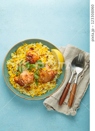 Traditional Indian dish chicken biryani with cilantro and lemon in a bowl top view on blue background Traditional Indian dish chicken biryani with cilantro and lemon in a bowl top view on blue background 123308060