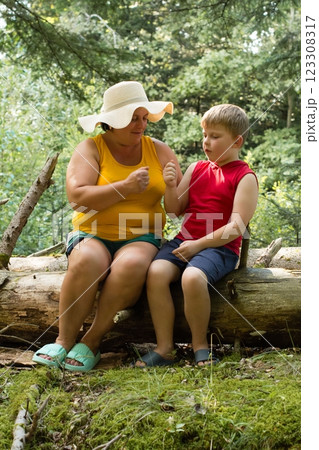 A woman and child sit together on a log in a forest, sharing a quiet moment. A woman and child sit together on a log in a forest, sharing a quiet moment. 123308317