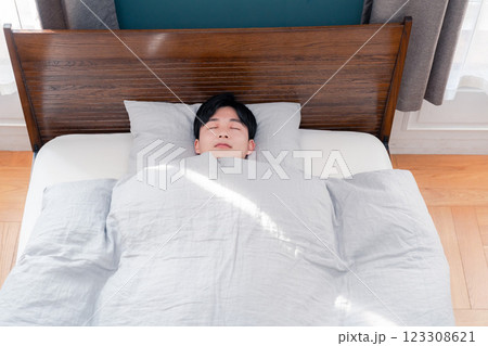 朝日が差し込む中で寝る若い男性 123308621