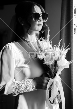 Elegant bride in a white dress, holding a bouquet, sunlight streaming in. Elegant bride in a white dress, holding a bouquet, sunlight streaming in. 123308732