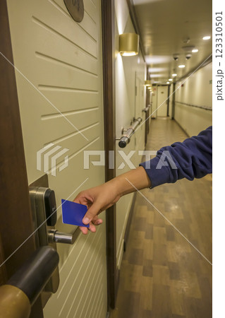 A hand holding a blue card key near a hotel door lock in a long hallway, key electronic lock, hotel room, holidays in mallorca, spain 123310501