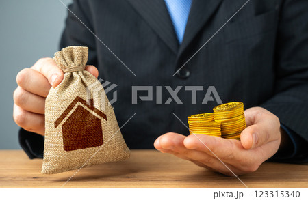 Businessman holding a bag with a house symbol and money coins. Sale of building permits. Housing stock, fees and payments for maintenance and repairs. Businessman holding a bag with a house symbol and money coins. Sale of building permits. Housing stock, fees and payments for maintenance and repairs. 123315340