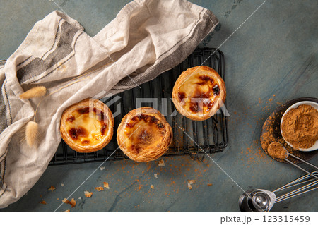 Three freshly baked Portuguese custard tarts on a cooling rack Three freshly baked Portuguese custard tarts on a cooling rack 123315459