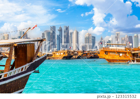 Traditional arab dhow fishermen boats anchored at pier with Doha modern business downtown center skyscrapers, Qatar 123315532