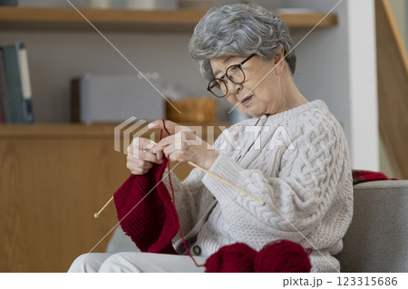困った顔で編み目を見つめる編み物をする80代の女性 困った顔で編み目を見つめる編み物をする80代の女性 123315686