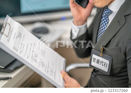 代行として電話営業をする男性社員 代行として電話営業をする男性社員 123317260