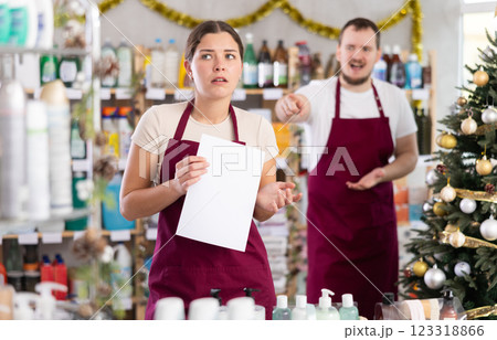 Frustrated salesgirl scolded by manager standing with paper in festive store Frustrated salesgirl scolded by manager standing with paper in festive store 123318866