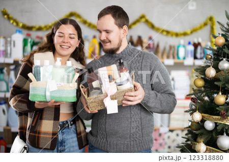 Young couple choosing gift sets with toiletries in Christmas decorated store Young couple choosing gift sets with toiletries in Christmas decorated store 123318880