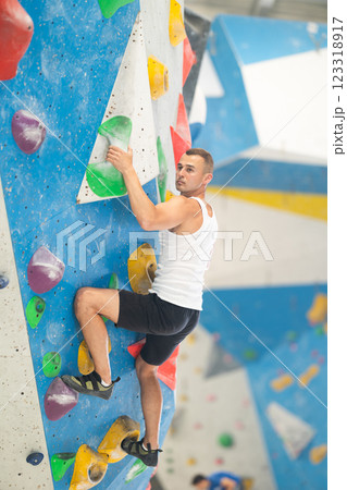 Sporty man in doing difficult wall climb in climbing gym without special climbing equipment 123318917