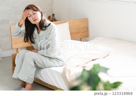起きてベッドの上で悪寒を訴える女性 123318968