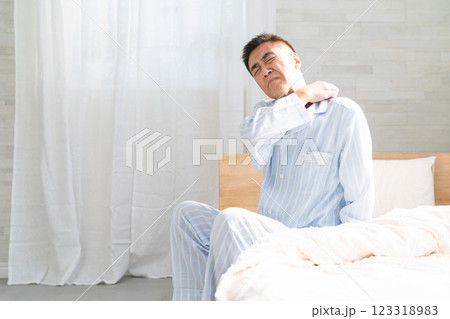 起きてベッドの上で肩を揉む男性 起きてベッドの上で肩を揉む男性 123318983