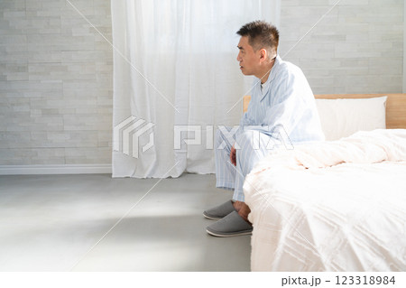 起きてベッドの上でうなだれる男性 起きてベッドの上でうなだれる男性 123318984