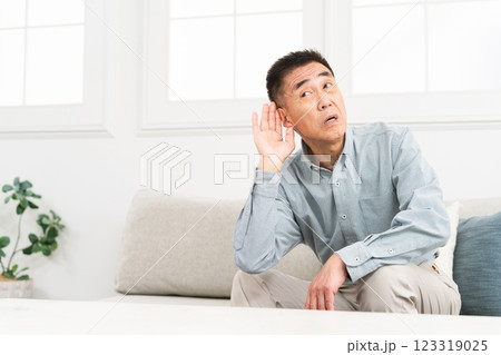 耳に手を当てて聞きかえす熟年男性 123319025