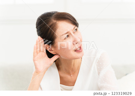 耳に手を当てて聞きかえす熟年女性 123319029