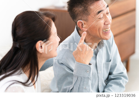 補聴器を付けた熟年男性と喜ぶ女性 補聴器を付けた熟年男性と喜ぶ女性 123319036