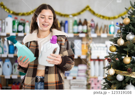 On New Year Eve, woman choose and buy liquid washing powder and tile cleaner spray 123319108