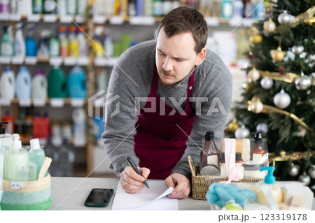 Male salesman makes notes on paper - keeps track of the receipt and expenditure of goods in supermarket Male salesman makes notes on paper - keeps track of the receipt and expenditure of goods in supermarket 123319178
