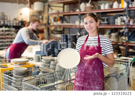 Enthusiastic female ceramicist demonstrating handcrafted plates in studio Enthusiastic female ceramicist demonstrating handcrafted plates in studio 123319225