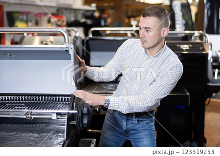 Young man chooses BBQ grill in store 123319253