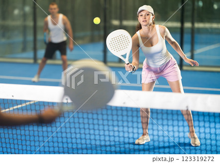 Adult woman and young man playing tennis against woman Adult woman and young man playing tennis against woman 123319272