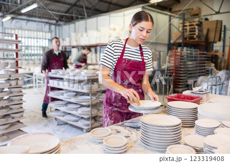Young woman cleaning blanks of ceramic products 123319408