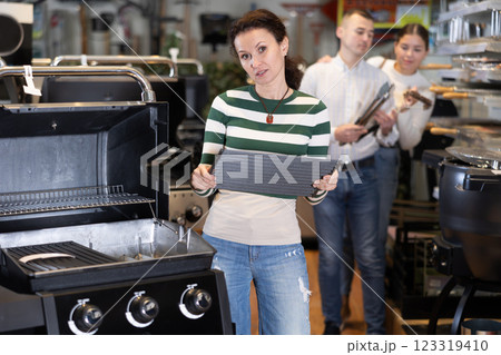 Adult woman chooses BBQ grill in store 123319410