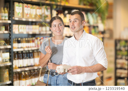 Man with package of eggs in hands talks with wife about buying ingredients for making homemade pie. 123319540